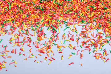 Colorful sprinkles on light grey background, flat lay. Confectionery decor