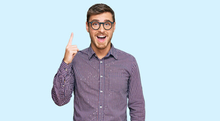 Fototapeta premium Handsome caucasian man wearing casual clothes and glasses pointing finger up with successful idea. exited and happy. number one.