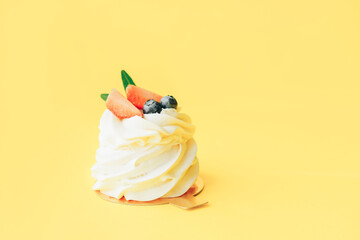 Delicious pastries covered with white and berry cream standing against yellow background