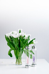 Quartz crystal bottles on a white table with white tulips for holistic and spiritual living, drink water