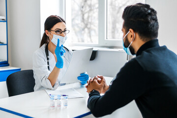 A female doctor consults her patient and holds documents in her hands, the patient listens