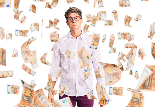 Young handsome man wearing business clothes and glasses puffing cheeks with funny face. mouth inflated with air, crazy expression.