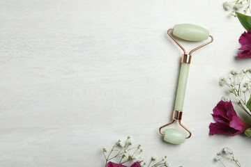Natural jade face roller and flowers on light background, flat lay. Space for text © New Africa