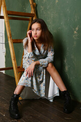 model girl in long printed dress and black boots full body portrait on dark wall background 