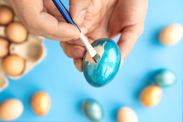 Preparing for Easter. Father painting Easter eggs on blue background. Easter day.