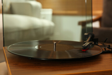 Modern vinyl record player with disc on table indoors, closeup