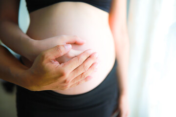 Belly of a pregnant woman with hand on 24 week (6 month)