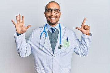 Hispanic adult man wearing doctor uniform and stethoscope showing and pointing up with fingers number seven while smiling confident and happy.