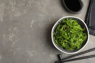 Japanese seaweed salad served on grey table, flat lay. Space for text