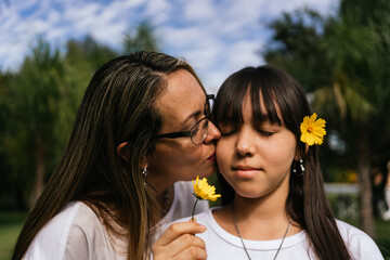 Portrait of Latina mother and daughter kissing each other.