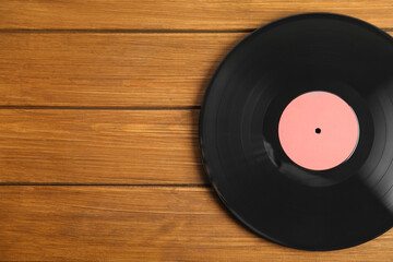Vintage vinyl record on wooden table, top view. Space for text