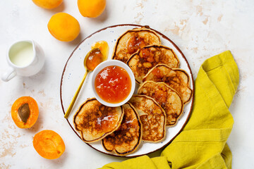 Homemade pancakes with fresh apricot fruit and jam on a light slate, stone or concrete background. Top view with copy space