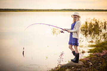 a girl fisherman in a blue dress and hat caught a perch, Selective focus