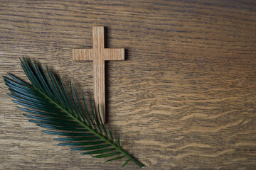 Palm sunday background. Cross and palm on wooden background.