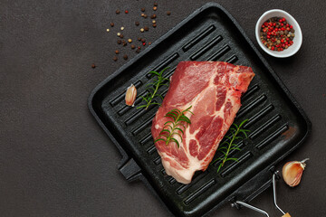 Raw beef steak with spices on a dark board. Top view