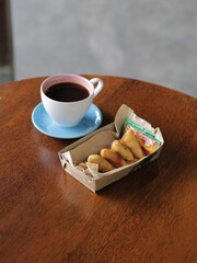 Hot Americano and snack on the table. Long black coffee on March 22nd, 2021 Yogyakarta, Indonesia.