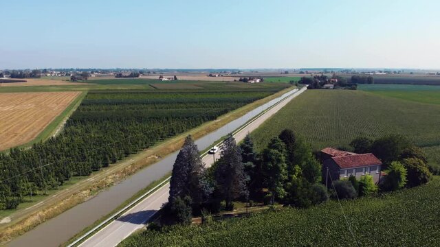 Aerial view of agricultural fields corn, Peach. road. Irrigation canal. Summer day. Bologna. Italy Emilia Romagna Ca Matte