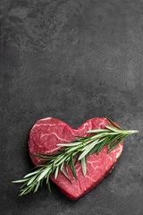 Tuinposter Heart shape raw fresh beef steak with rosemary stick on metal background © lena_zajchikova