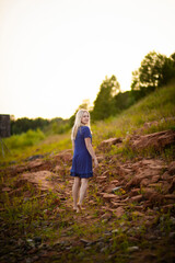 Beautiful young blonde in blue dress stend on red rocks, Selective focus