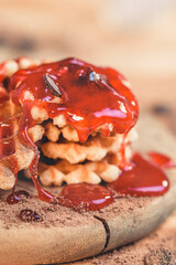 Close-up of mini waffles with strawberry syrup and chocolate shavings.