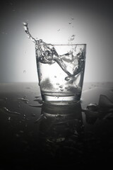 Water splash in glass with ice cubes.