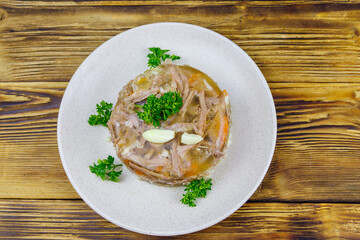 Meat aspic in a plate on a wooden table. Top view. Traditional russian dish