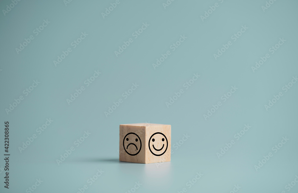 Poster smile face and sadness face print screen of two side of wooden cube block on blue background, emotio