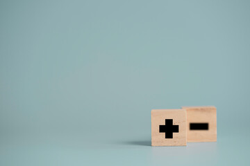 Plus sign in front of minus sign which print screen on wooden cube block and copy space, positive...