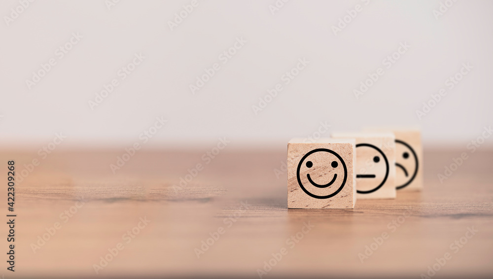Poster Smiley face in front of normal and sadness face which print screen on wooden cube block, emotion selection for customer satisfaction and evaluation concept.