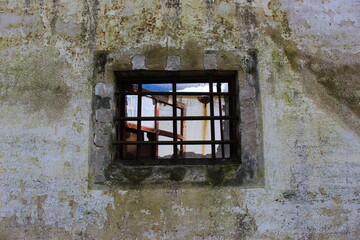 old window with bars on old wall