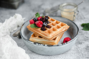 Belgian waffles with berries on a light plate.Breakfast