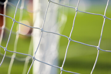 Soccer football equipment. White soccer net on a goal. Soccer net nodes. Blurred goal post in the background
