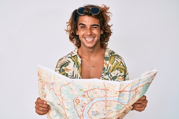Young hispanic man wearing summer style holding map winking looking at the camera with sexy...