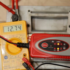 Smart automatic charger unit on digital multimeter volt meter display with 12.74 volts digit with...