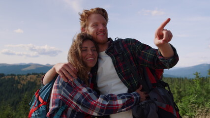 Hikers hiking in mountains. Happy woman and man looking around green landscape