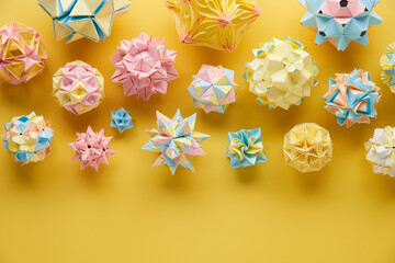 Set of multicolor handmade modular origami balls or Kusudama Isolated on yellow background. Visual...
