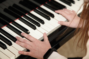Hands of a white European little pianist girl playing the Grand piano closeup top side view, classic music school education