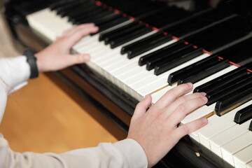 Fototapeta na wymiar White hands of a piano girl playing the Grand piano closeup top side view, classic music school education