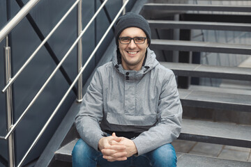 Street style portrait of handsome 30-35 years old man outdoors sitting on the stairs