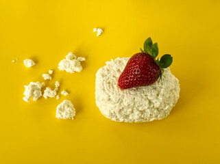 Fresh curd with red strawberry on yellow background. Cottage cheese and red berry breakfast concept. Food minimalism. Calcium and protein source. Modern food aesthetic