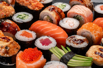 Assorted sushi nigiri and maki big set on slate. A variety Asian food with tuna, crab, salmon, eel and rolls.