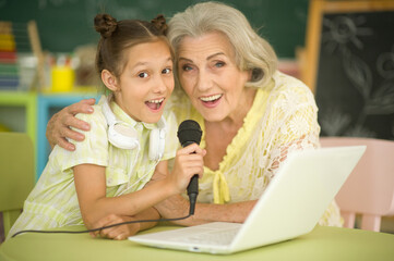 portrait of  grandmother and granddaughter singing karaoke