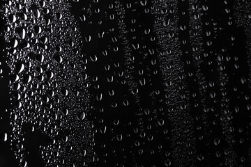Water droplets on black crylic background. Rain drops perched on glass on a black background