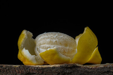 Lemon on a dark background. A peeled lemon lies in a peel on a black background. Creative photo of lemon.