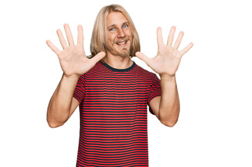 Caucasian man with blond long hair wearing casual striped t shirt showing and pointing up with fingers number ten while smiling confident and happy.