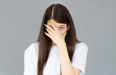 Young woman with hand on her face isolated on gray background, facepalm