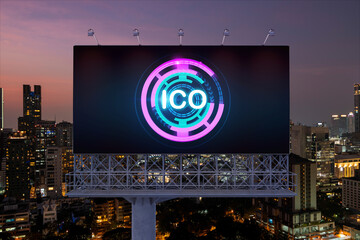 ICO hologram icon on billboard over panorama city view of Bangkok at night time. The hub of blockchain projects in Southeast Asia. The concept of initial coin offering, decentralized finance
