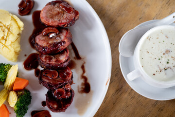 Pork fillet wrapped in bacon served with boiled vegetable and mushroom soup