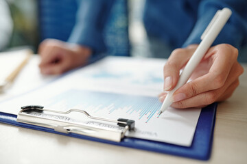 Close-up image of businesswoman pointing at column chart when analyzing data , selective focus