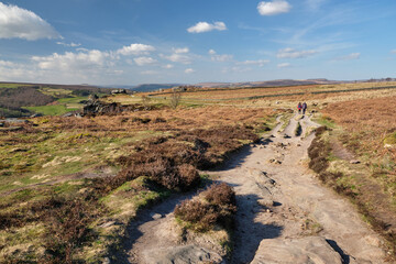 People walking along the path above Froggatt Edge, Peak District, UK